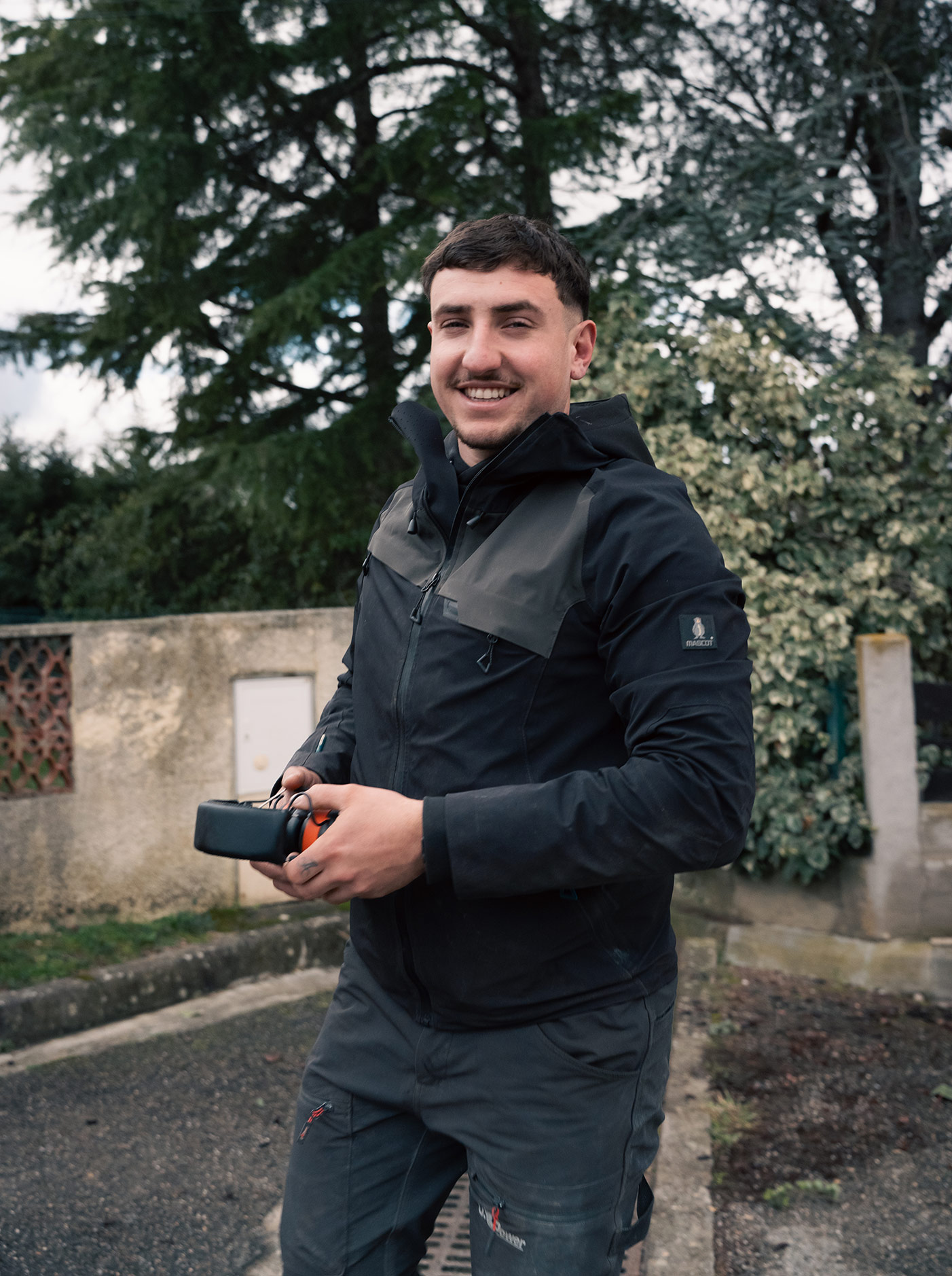Paysagiste ferrai aménagement à Carcassonne souriant dans un jardin verdoyant avec murs en pierre